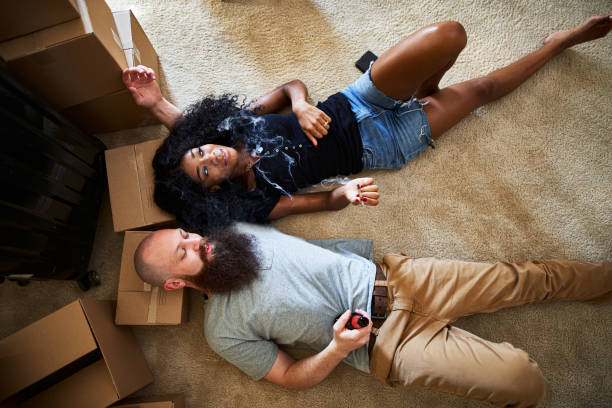 interracial couple relaxing after hard work moving by smoking marijuana joint together while laying on floor