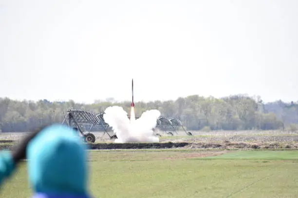 A large model rocket takes off from a launchpad.