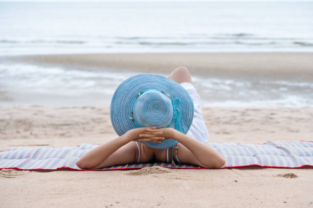 istock female with hat relaxing on beach mat by beach 1152317452
