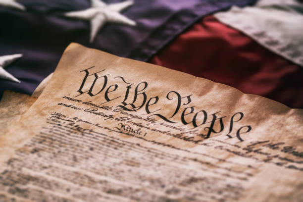United States Constitution on American Flag We The People - An old USA Constitution on parchment paper lying on a old American flag. democracy stock pictures, royalty-free photos & images