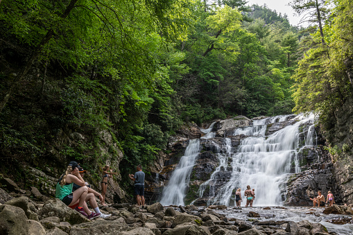 Hampton, Tennessee, USA - May 27, 2019: People, including a woman holding a baby, enjoy Memorial Day at the cool waters of Laurel Falls in Carter County, Tennessee.