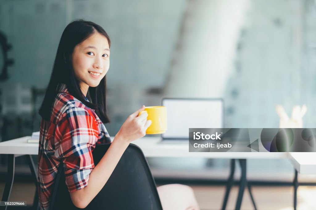 Young casual woman is relaxing with nice coffee. Young beautiful casual woman holding a coffee cup while sitter at her working place. Relax with nice coffee. Image Montage Stock Photo