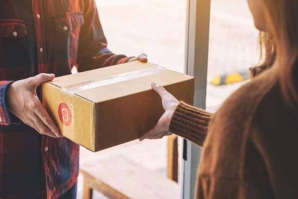 istock woman receiving parcel box from delivery man 1152333340