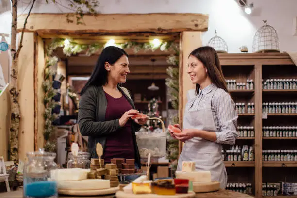 Photo of Cheerful shopkeeper helping customer in packaging free shop.