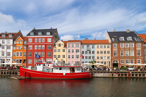Copenhagen, Denmark â June 14, 2017: Port of Nyhavn is a tourist attraction of the city. Old wooden ship and colorful houses on the waterfront. Canals of Copenhagen.