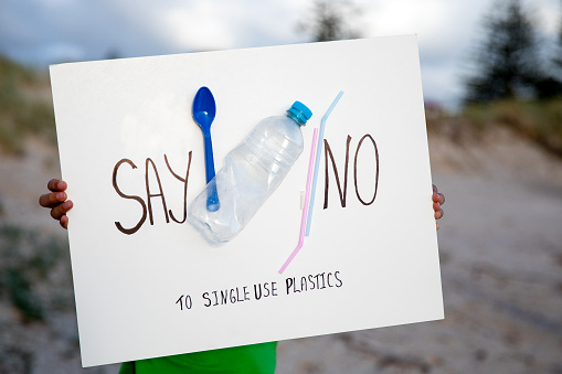 A sign reading say no to single use plastics held by a child.