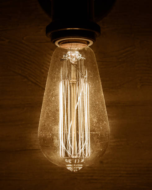 istock Edison vintage light bulb, retro light bulb in dark room and concrete wall as background 1152346535