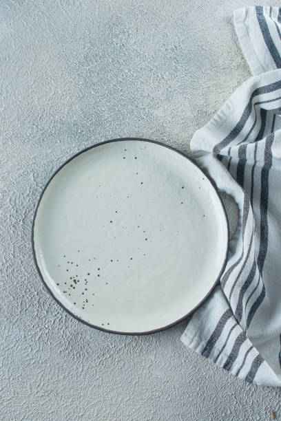 istock Empty ceramic plate and kitchen striped towel on light stone concrete table background. Copy space. Menu Recipe Concept. Top view. Flat lay 1152348425