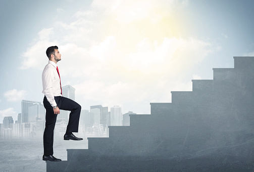 Businessman climbing up a concrete staircase concept on city background