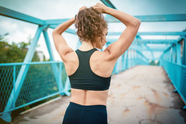 Athletic woman making ponytail before sports training Back view of athletic woman making ponytail before sports training outdoors woman tying hair in ponytail getting ready for exercising stock pictures, royalty-free photos & images