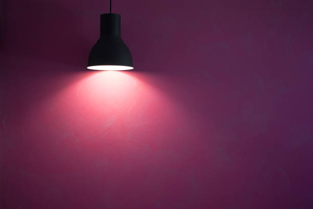 istock Red wall illuminated by vintage black stylish cone lamp. 1152354318