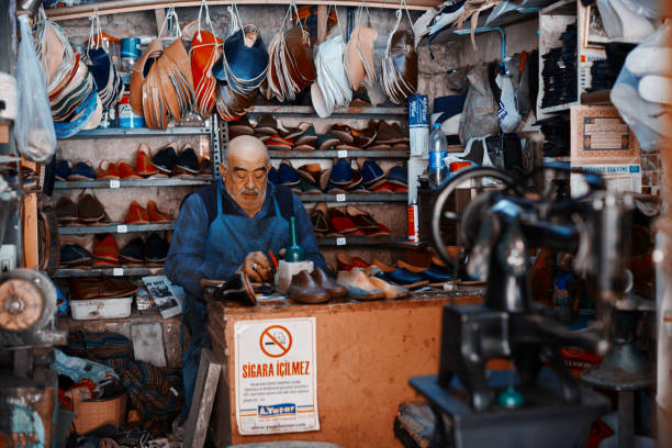 ältere handwerkshoemaker, die traditionelle schuhe, die als "yemeni" bekannt sind, in seiner werkstatt herstellen. - men hat leather senior adult stock-fotos und bilder