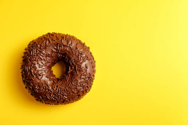 istock chocolate donut on yellow background top view 1152362293