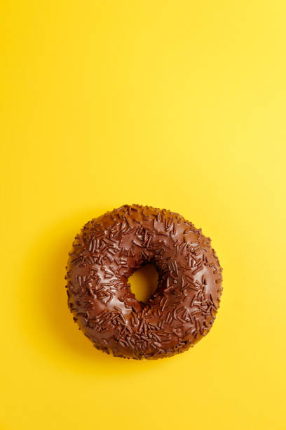 istock chocolate donut on yellow background top view 1152362640
