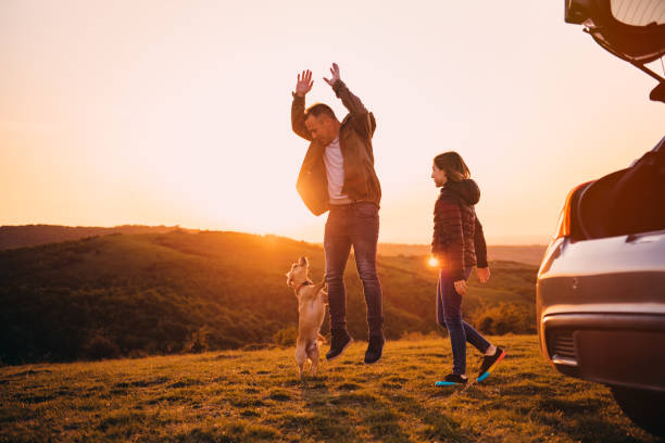 Father and daughter playing with dog at hill camping Father and daughter playing with small yellow dog at hill camping during sunset hopper car stock pictures, royalty-free photos & images