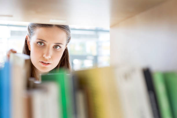 istock Closeup of young student searching book on shelf at library 1152367324