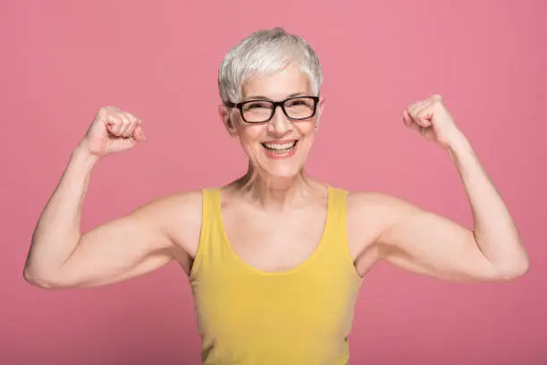 Senior fit woman showing her muscles