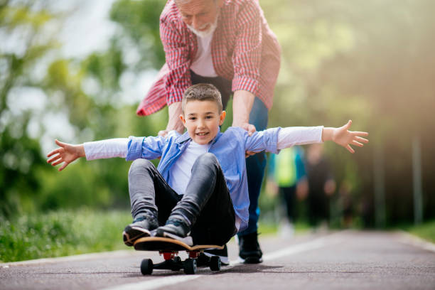 istock Grandfather and grandson skateboarding together 1152372231