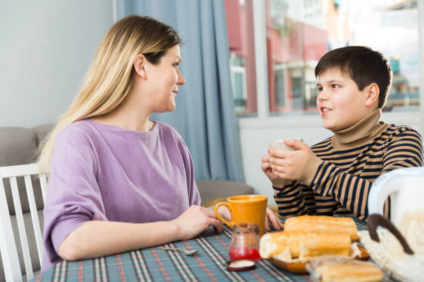 istock Young woman and son chatting at table with tea indoors 1152373594