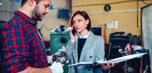 istock Female engineer standing with machinist and talking on the phone with client 1152376539
