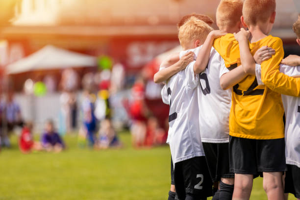 kids sport team gathering. kinder spielen sport. jungs in sportswear jersey uniforms having shout team. jugendsport für kinder. hintergrund der jugendfußball-akademie mit kopierplatz - soccer child coach childhood stock-fotos und bilder