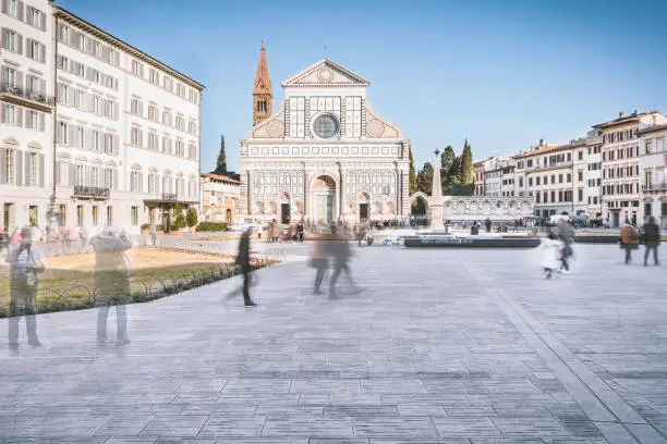 low angled view on Piazza Santa Maria Novella square with the main front of Santa Croce Church.  Ghostly tourist's figures wandering around