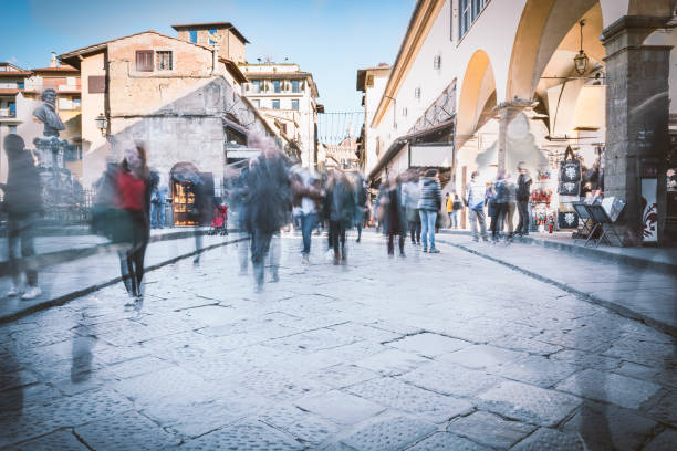 low angled view from the middle of Ponte Vecchio Bridge in Firenze - Tuscany.\nGhostly tourist's figures wandering on the bridge