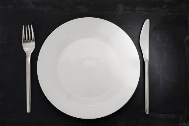 istock Top view of a white plate, silverware on stone background. 1152383080