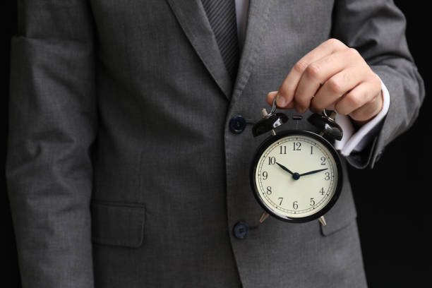istock Businessman's hand holding black alarm clock 1152385842