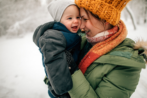 Little boy and his mom on a snowy, winter day enjoying first snow in a season
