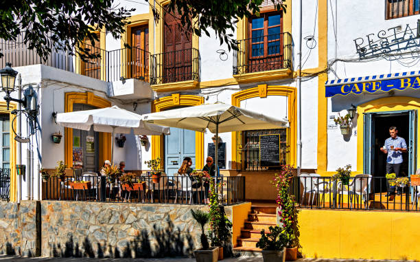 Tourists dine outdoors in the village of Nijar, Almeria, Spain. Tourists dine outdoors at a local restaurant in the picturesque village of Nijar in the province of Almeria, Spain. almeria stock pictures, royalty-free photos & images