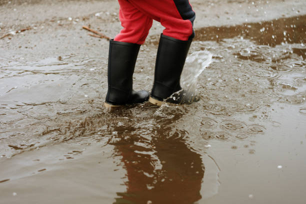 istock child walks after rain through the puddles in rubber boots 1152399524