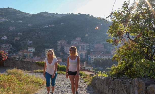 istock Female hikers walk along cobblestones above medieval town 1152401005