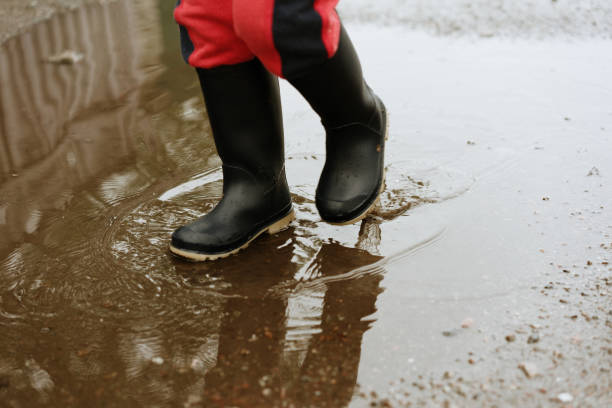 istock child walks after rain through the puddles in rubber boots 1152401371