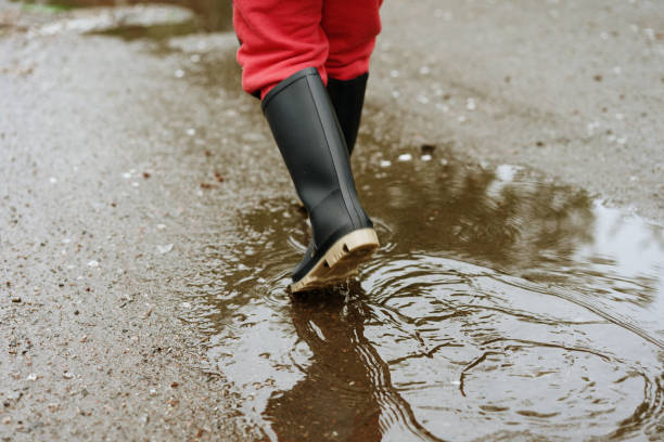 istock child walks after rain through the puddles in rubber boots 1152401571