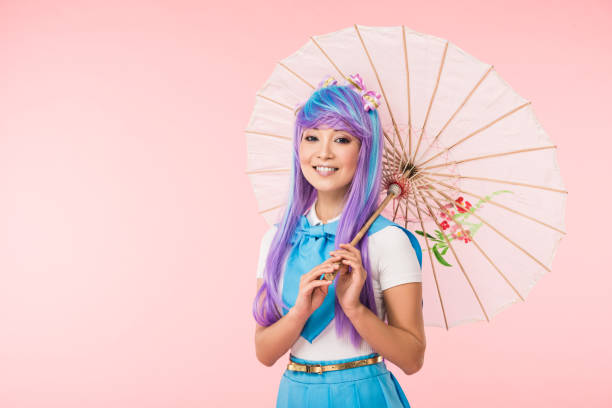 chica de anime asiática sonriente en peluca sosteniendo paraguas de papel aislado en rosa - cosplay de anime fotografías e imágenes de stock