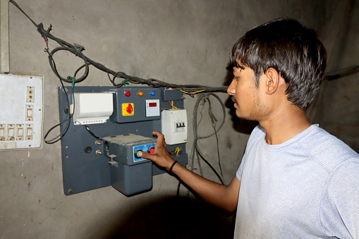 Young farmer pressing the motor button for irrigation.