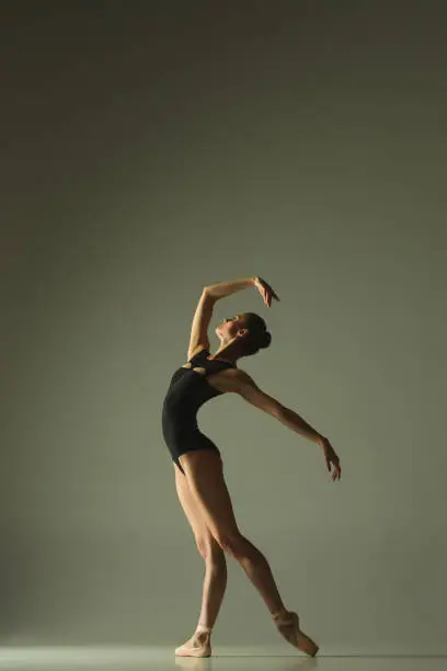 Photo of Young graceful female ballet dancer dancing in mixed light