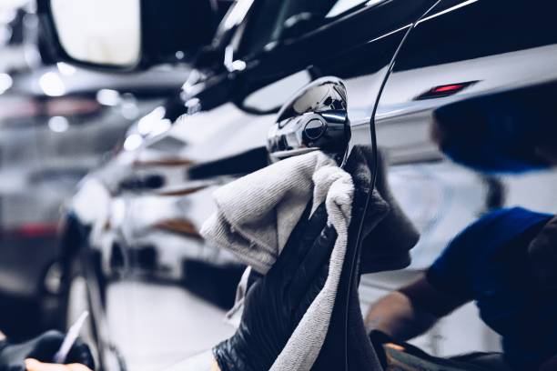 man worker in car wash polishing car with cloth - car wash car cleaning washing imagens e fotografias de stock