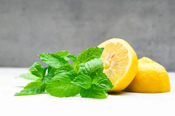 Photo of Lemon with mint against a grey wall background