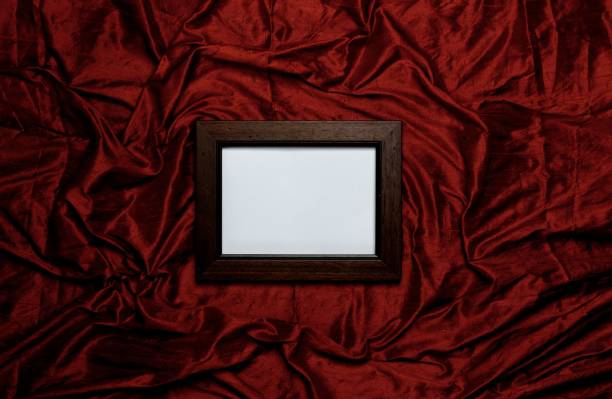 istock Wooden empty picture frame on the scarlet silk background 1152423293