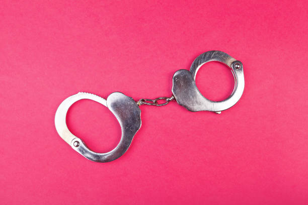 istock Metal handcuffs on bright pink background top view 1152423723