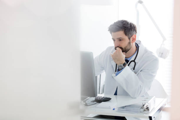 istock Serious doctor using computer at desk in hospital 1152425519