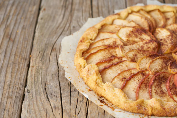 Apple pie, galette with fruits, sweet pastries on old wooden rustic table, side view, copy space