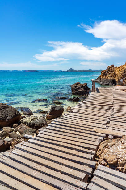 Wooden boardwalk with large rocks and clear turquoise sea stock photo
