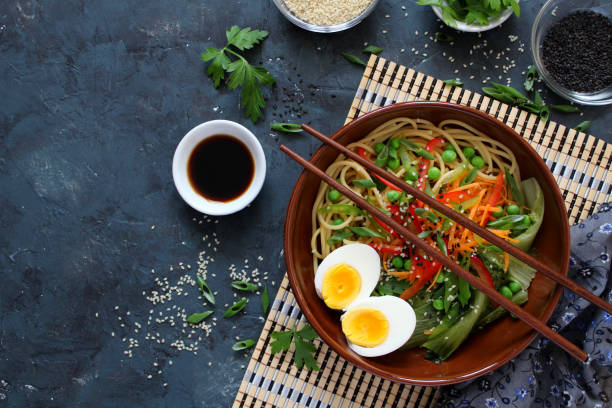 istock Noodles with vegetables and eggs in bowl on dark background. 1152432172
