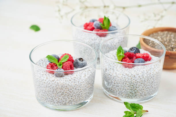 istock Chia pudding with fresh berries raspberries, blueberries. Three glass, light wooden background, side view, flowers, close up. 1152433625