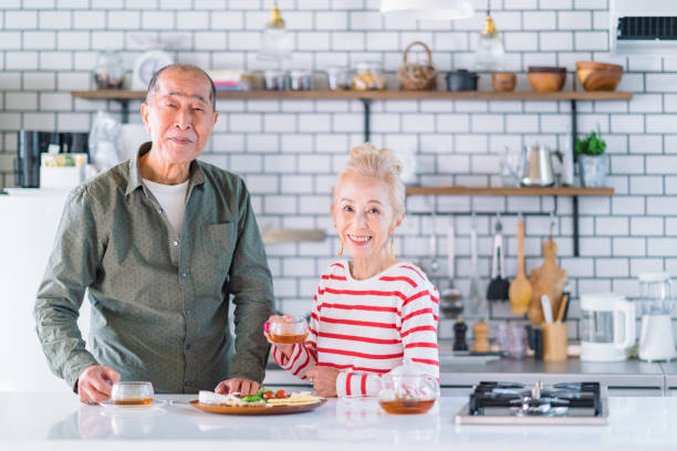 portrait of happy senior couple in kitchen - salad japanese culture japan asian culture imagens e fotografias de stock