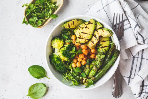 Buddha bowl with grilled avocado, asparagus, chickpeas, pea sprouts and broccoli. Vegan food concept.