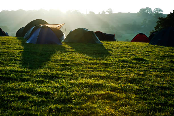 Large camping tent in a natural setting at sunset. Warm cozy light inside a camping tent.